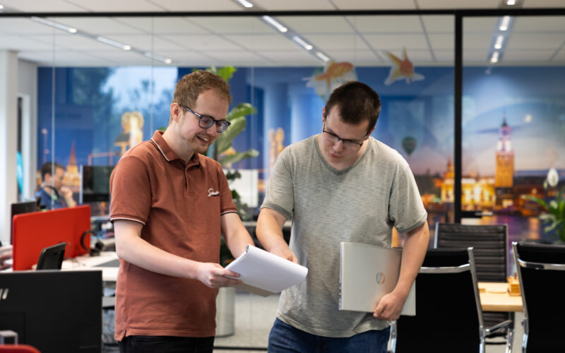 Twee softwareontwikkelaars van Microsign bespreken een C#-ontwikkelproject op kantoor.